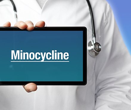 A dentist holding a tablet that says minocycline