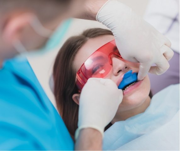 Young woman getting fluoride treatment from dentist