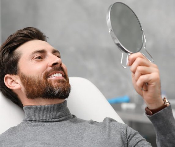a patient checking his new teeth with a mirror