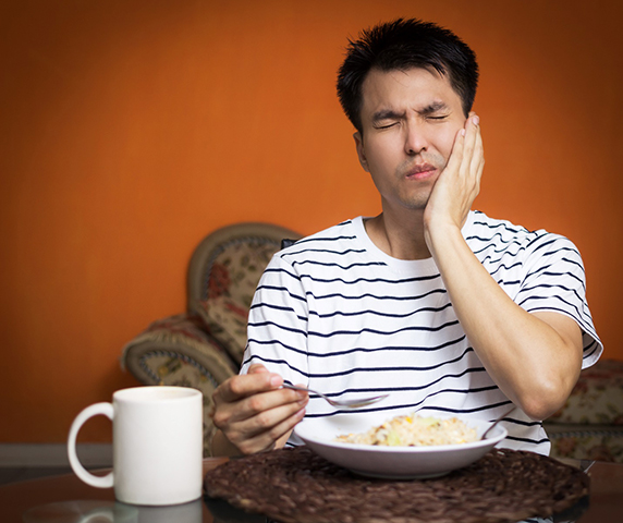 Man dealing with a toothache eating dinner