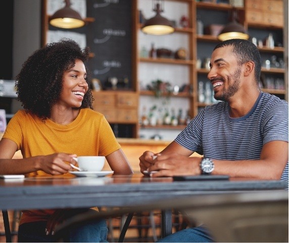 Smiling man and woman sitting at table in coffee shop