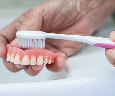 Someone brushes removable denture