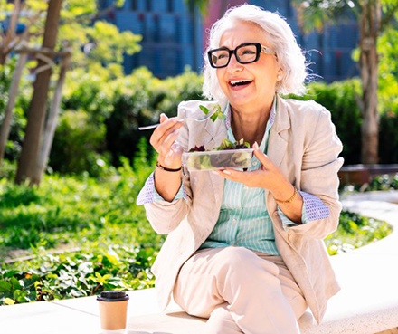 Lady smiles while eating salad