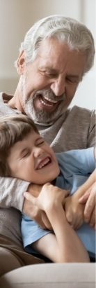 Senior man laughing with grandson on couch