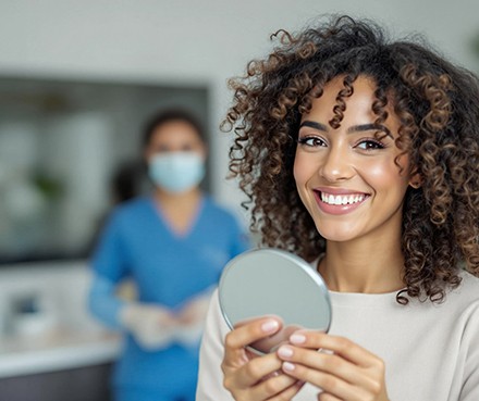 Woman smiling while holding small mirror