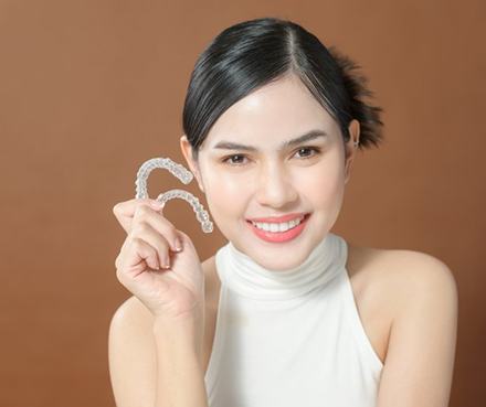 Lady smiles showing off Invisalign aligners