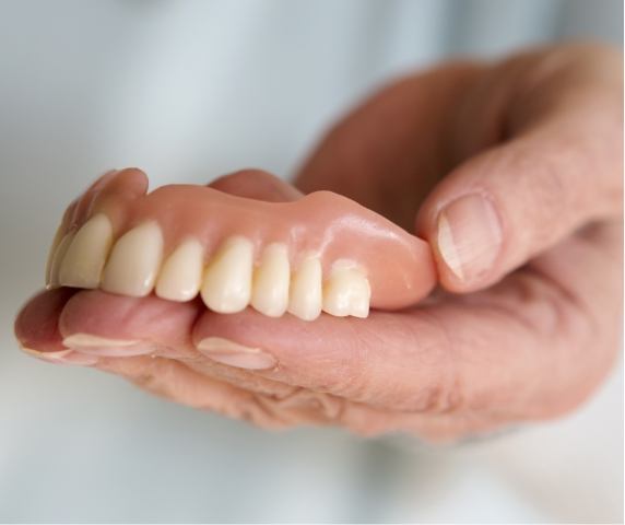 Dentist holding full upper denture in Vero Beach