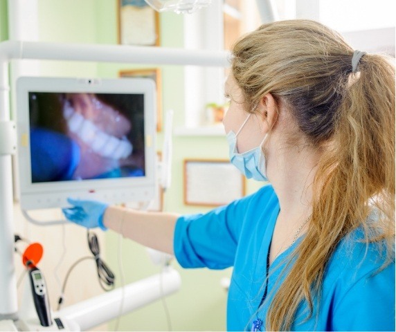 Dental team member looking at photos of teeth on screen thanks to advanced dental technology in Vero Beach