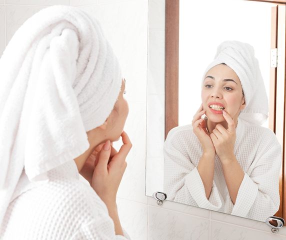 Woman looking at her teeth in bathroom mirror