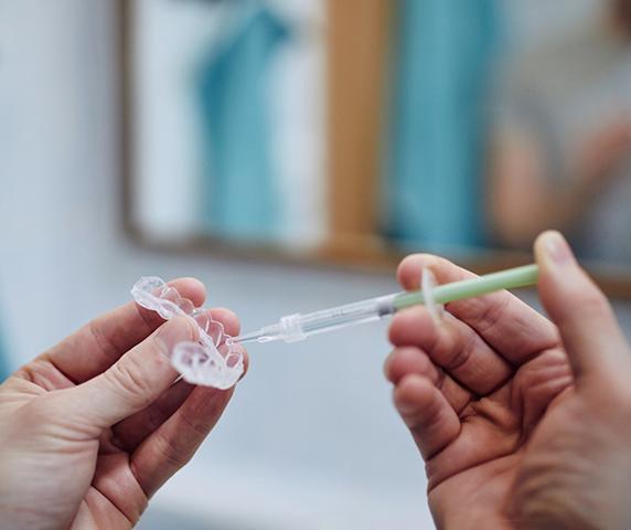 Patient using take-home teeth whitening gel and tray