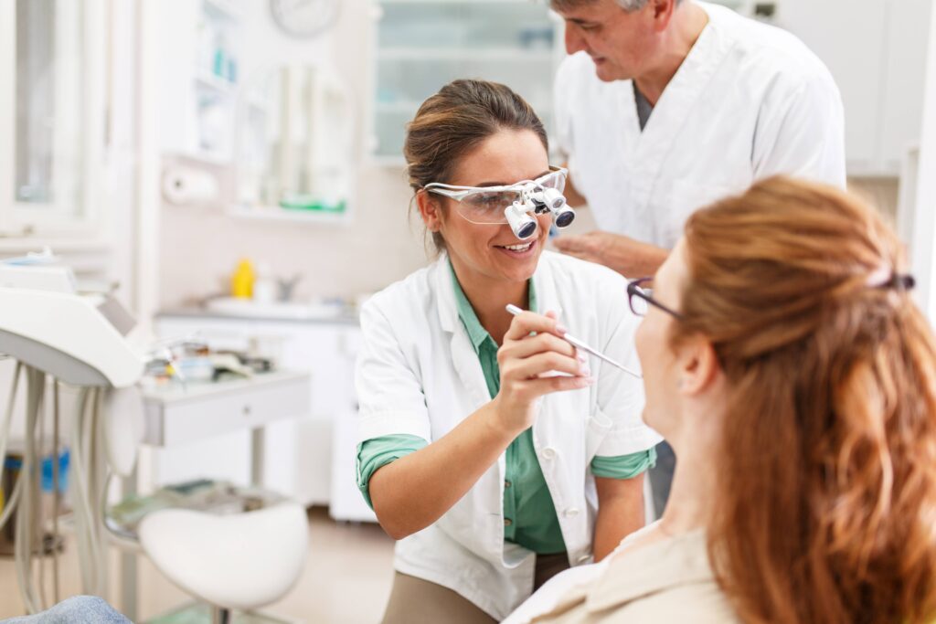 Smiling dentist looking at patient's teeth